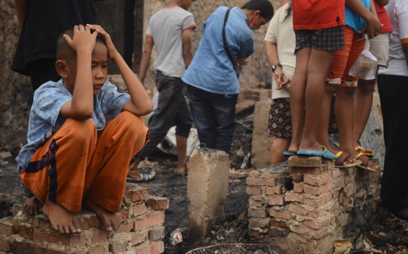 Seorang anak duduk di sisa pondasi sebuah rumah setelah terjadi kebakaran di kawasan Muara Baru, Penjaringan, Jakarta Utara, Sabtu (28/6/20114). Kebakaran yang belum diketahui penyebabnya itu mengakibatkan ratusan rumah habis terbakar.